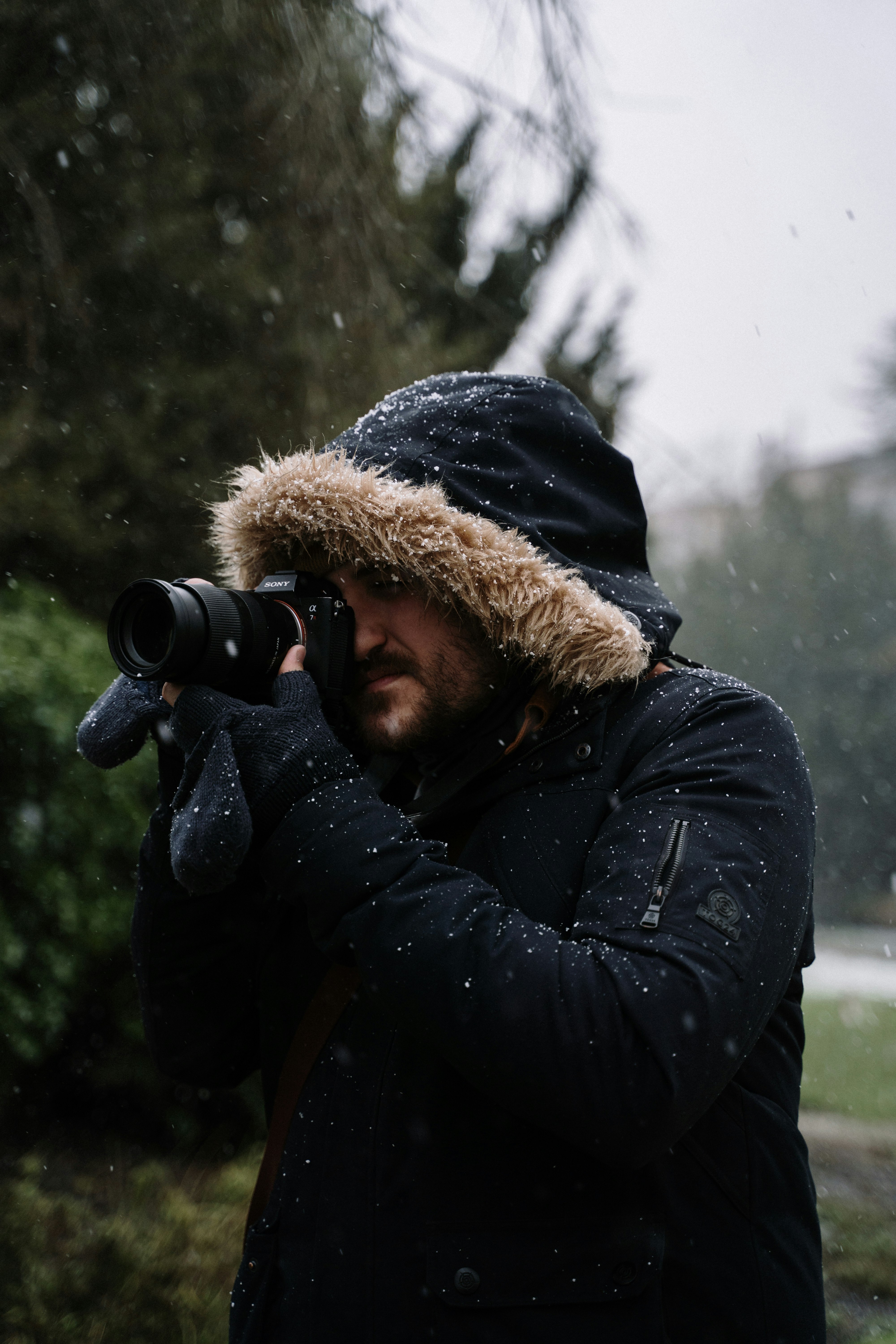 person in black jacket and brown knit cap holding black dslr camera